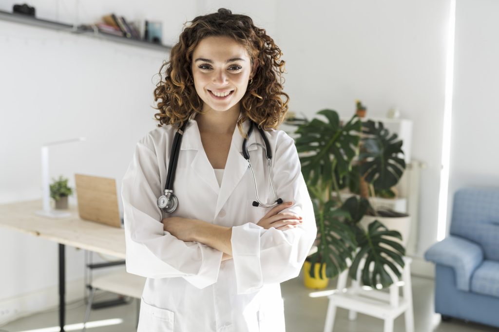 Happy young woman doctor with curly hair wears white medical